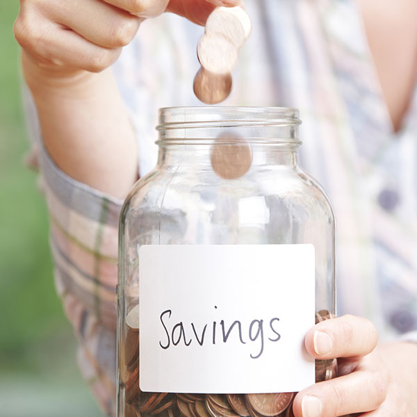 Woman Dropping Coins Into Jar Labelled Savings